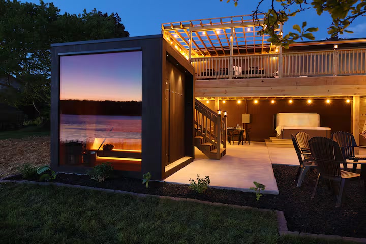 Glass-front sauna and lower patio beside Pearl Lake at dusk